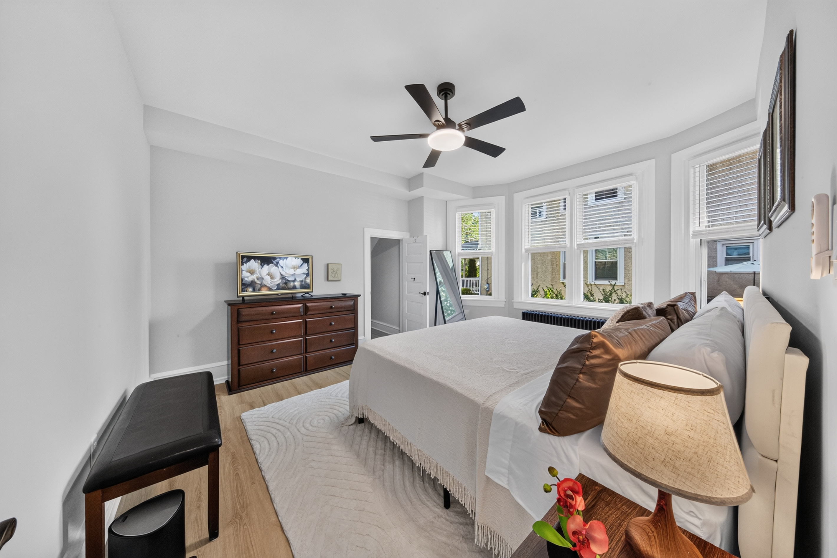 Ample dresser storage, flat-screen smart TV, and bright natural morning light.