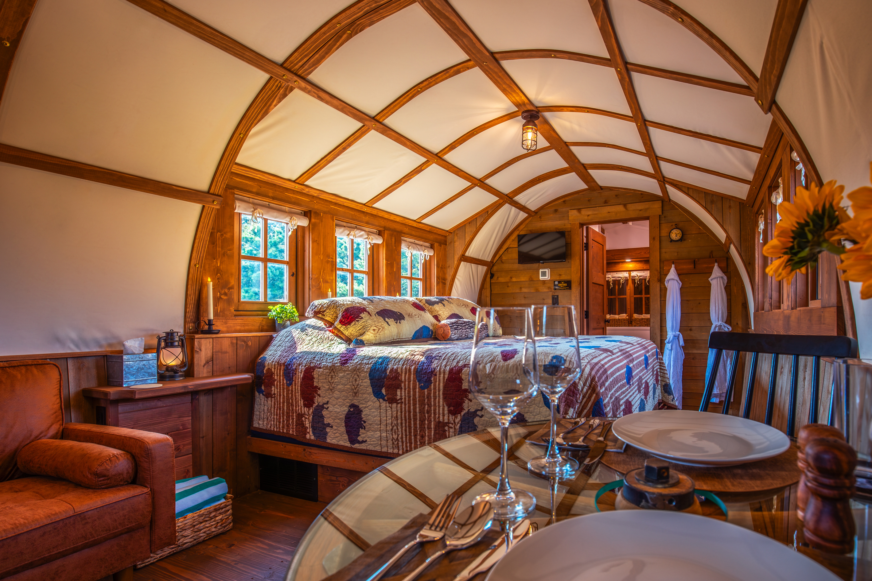Romantic dining for two inside the wagon with cozy bed views and warm cabin-style lighting.