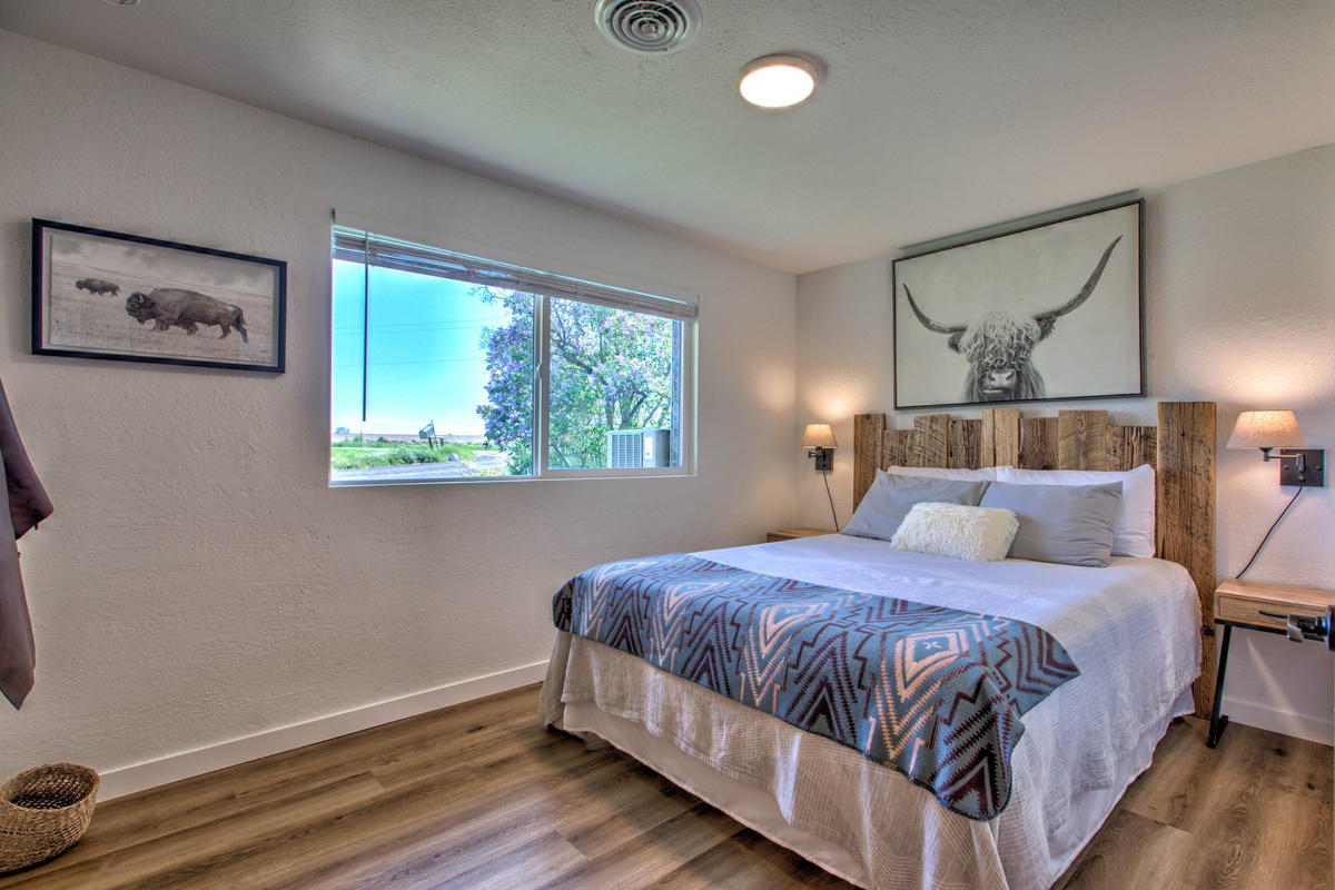 Queen bedroom — warm wood headboard, ranch-style art, and a sunny window