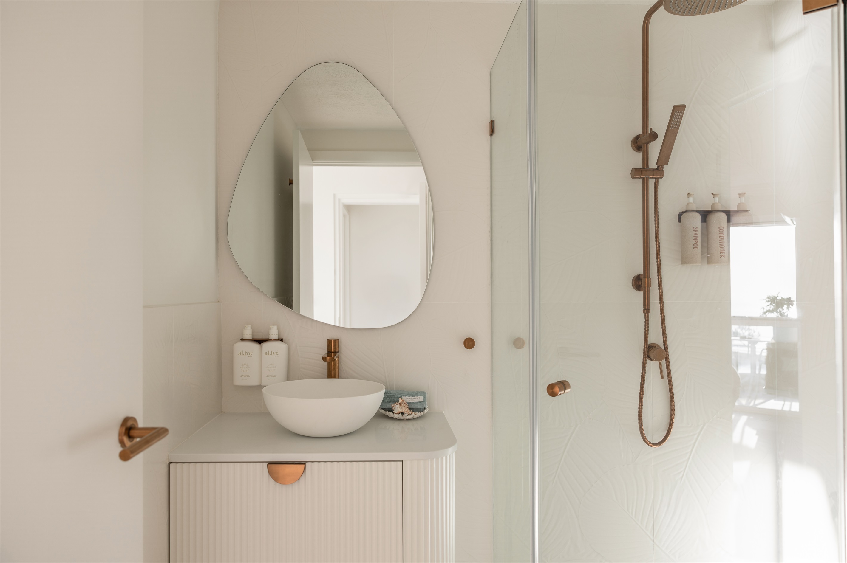 Modern studio bathroom - rainfall shower, quality amenities & elegant coastal design.