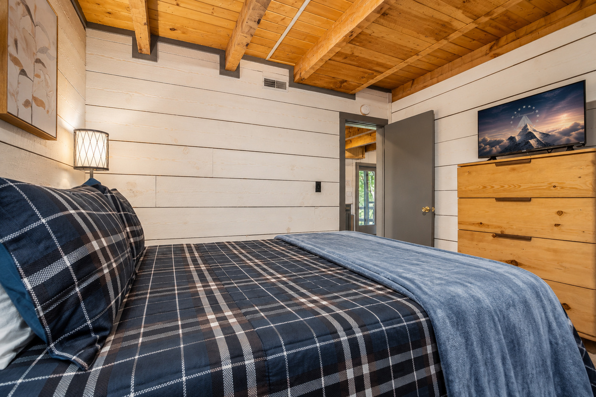 Lower level bedroom, with queen bed, dresser, and smart TV