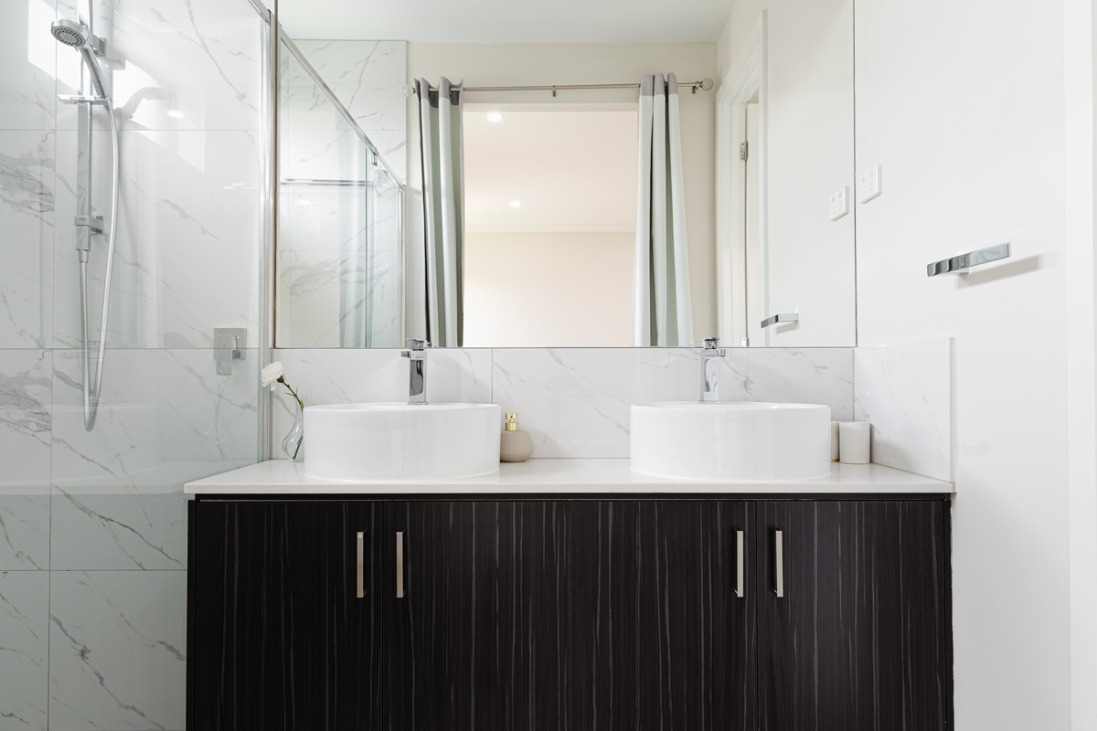The bathroom includes a large glass-screen shower, twin basins, vanity storage and mirror space, making daily routines easier during the stay.