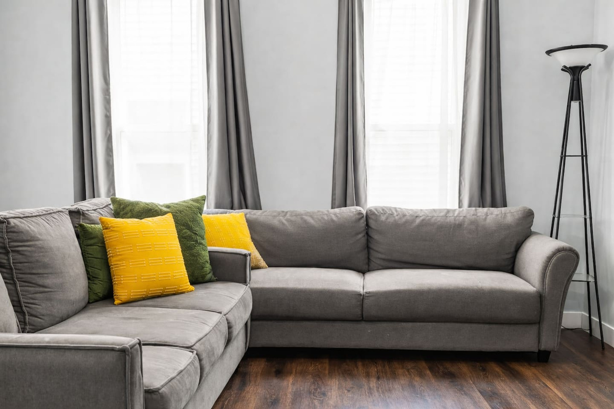Bright and airy living room anchored by a spacious sectional, tall windows, and warm natural light.