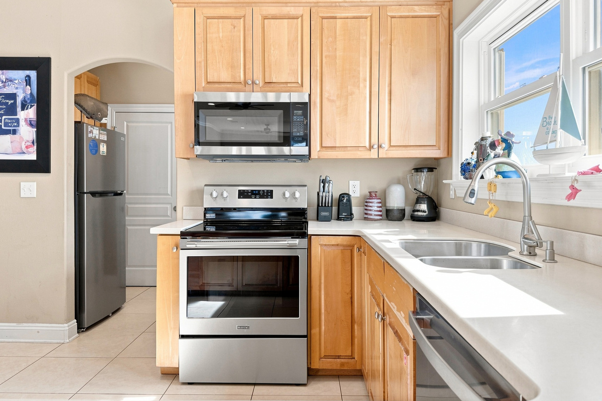 Kitchen with stainless steel refrigerator, range, and a bright window over the sink