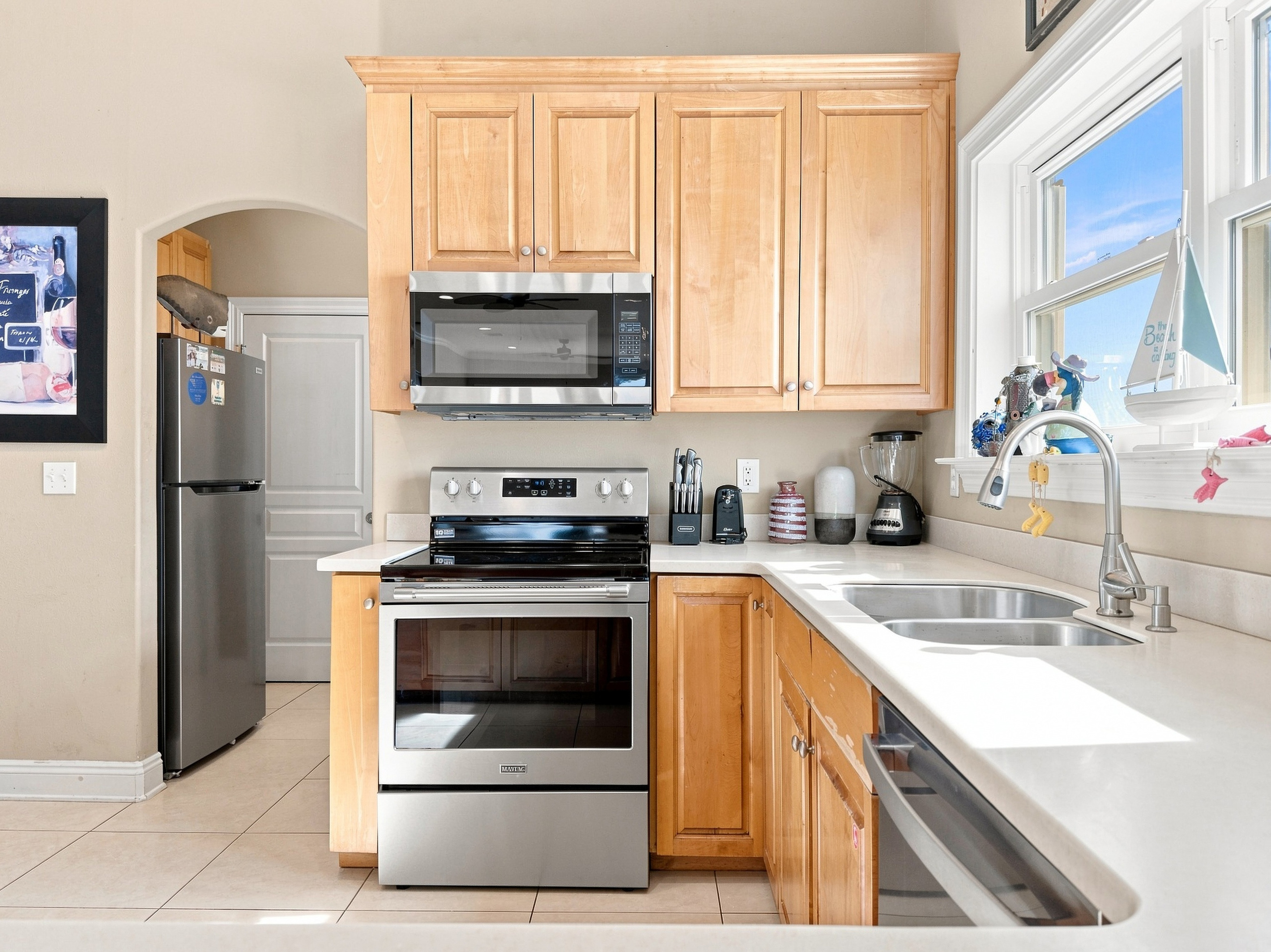 Kitchen with stainless steel refrigerator, range, and a bright window over the sink