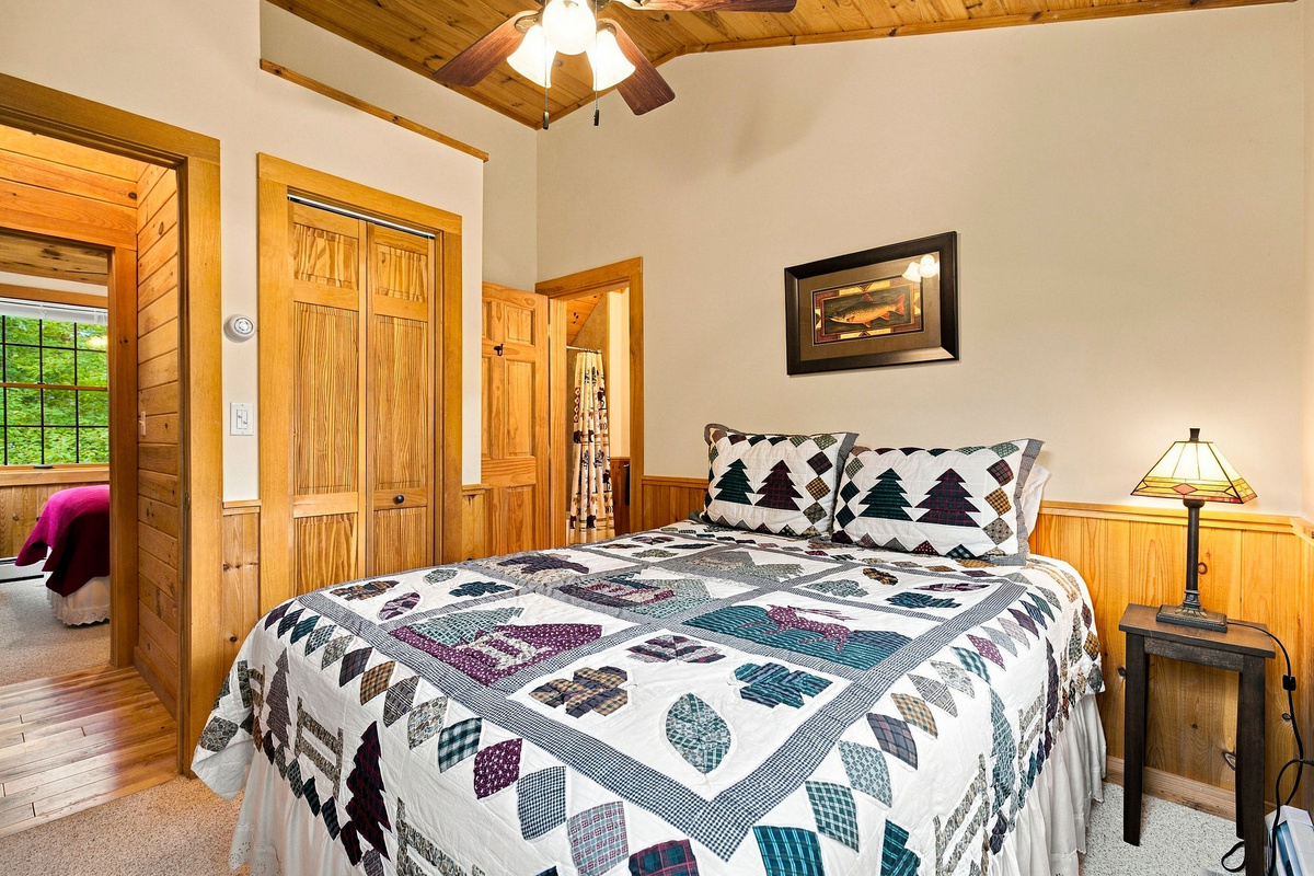 Comfortable queen bedroom with cozy Adirondack décor and warm wood accents.