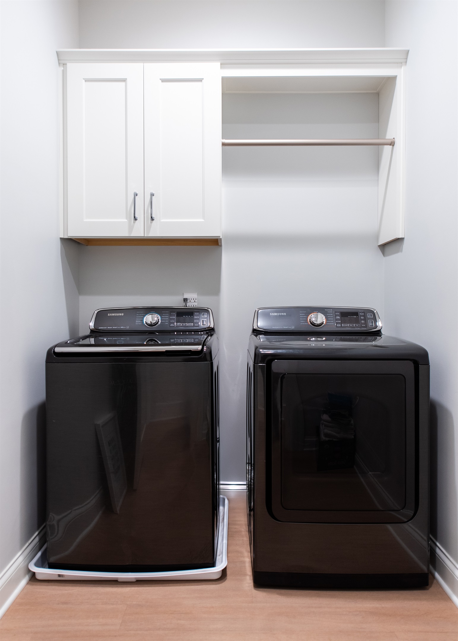 Simplify your stay with this well-organized laundry area, featuring modern Samsung washer and dryer units, ample storage, and a hanging rod for convenience. Perfect for extended visits on the Bourbon Trail.