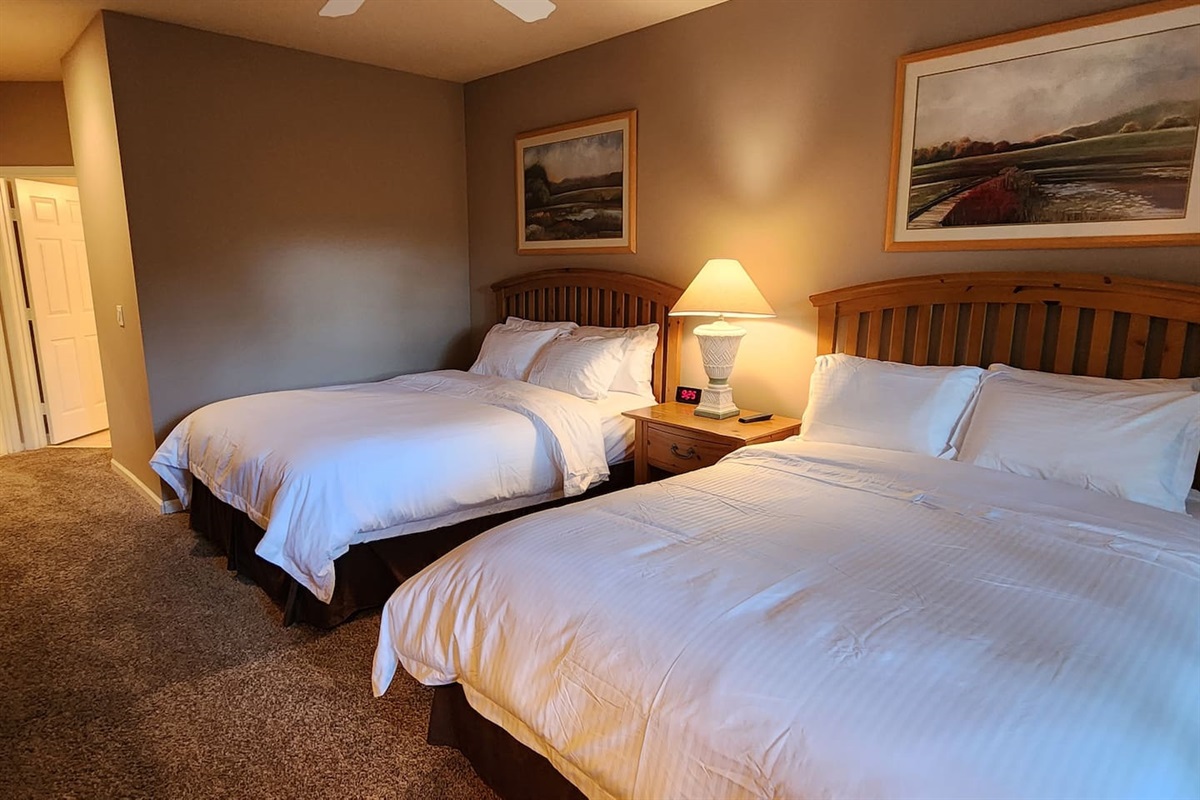 Spacious bedroom featuring two beds, warm lighting, and a relaxing setup for guests or family.