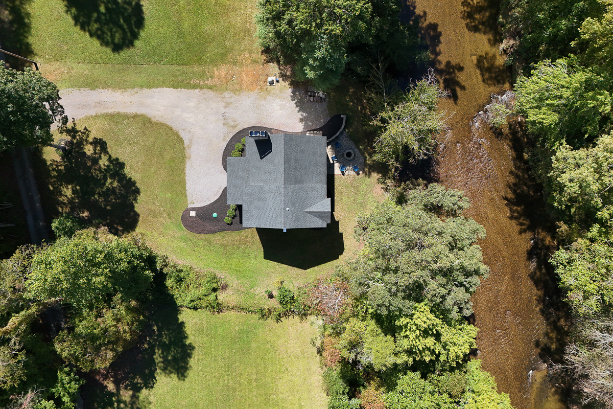An overhead view of Robbin’s Nest on Snowbird Creek highlights the grassy yard, gravel driveway, and fire pit just steps from the creek.