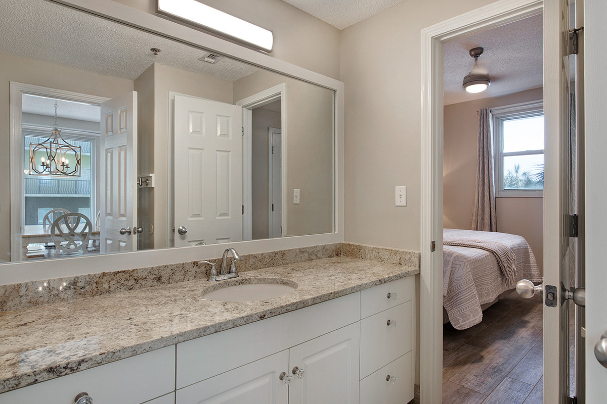 Guest bathroom with twin vanities and walk-shower accessible from living room