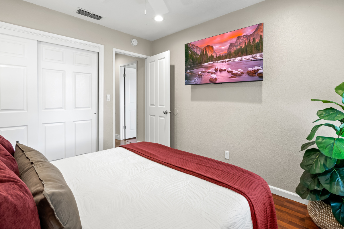 A comfortable bedroom designed for easy relaxation, complete with cozy bedding, ample storage, and a wall-mounted TV for entertainment.