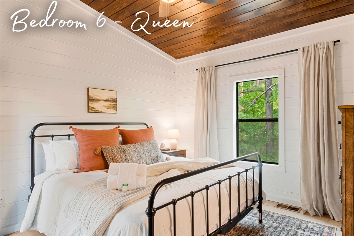 Dream peacefully in this queen bedroom that blends vintage vibes with modern comforts, surrounded by tranquil woodland views.