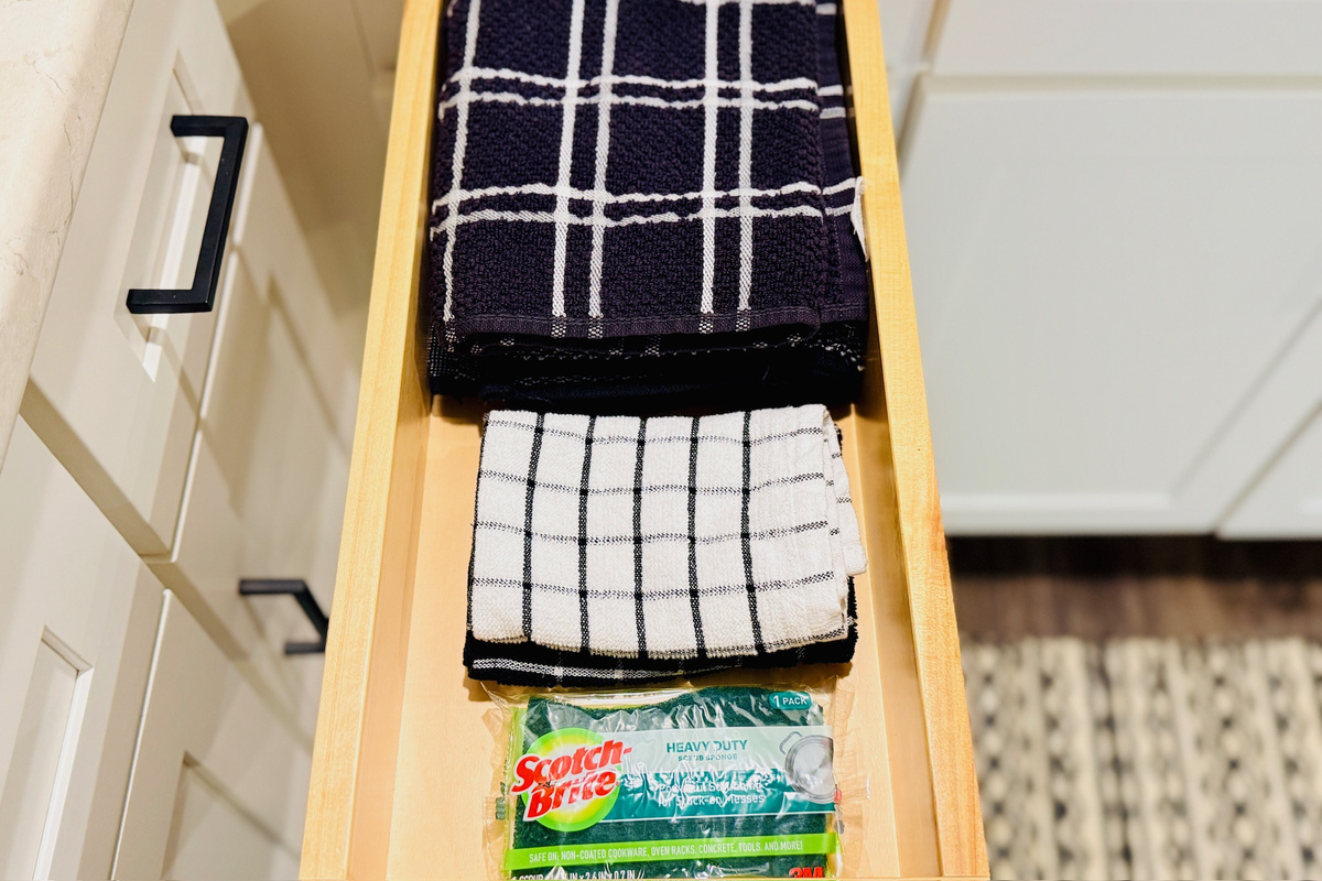 Dish towels, sponges, and kitchen-cleaning supplies are stored within easy reach.
