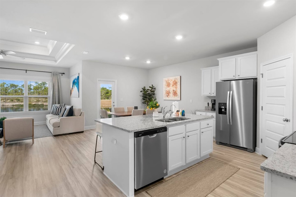 Spacious kitchen with 4-stool counter, top appliances, and seamless flow into dining and living areas.