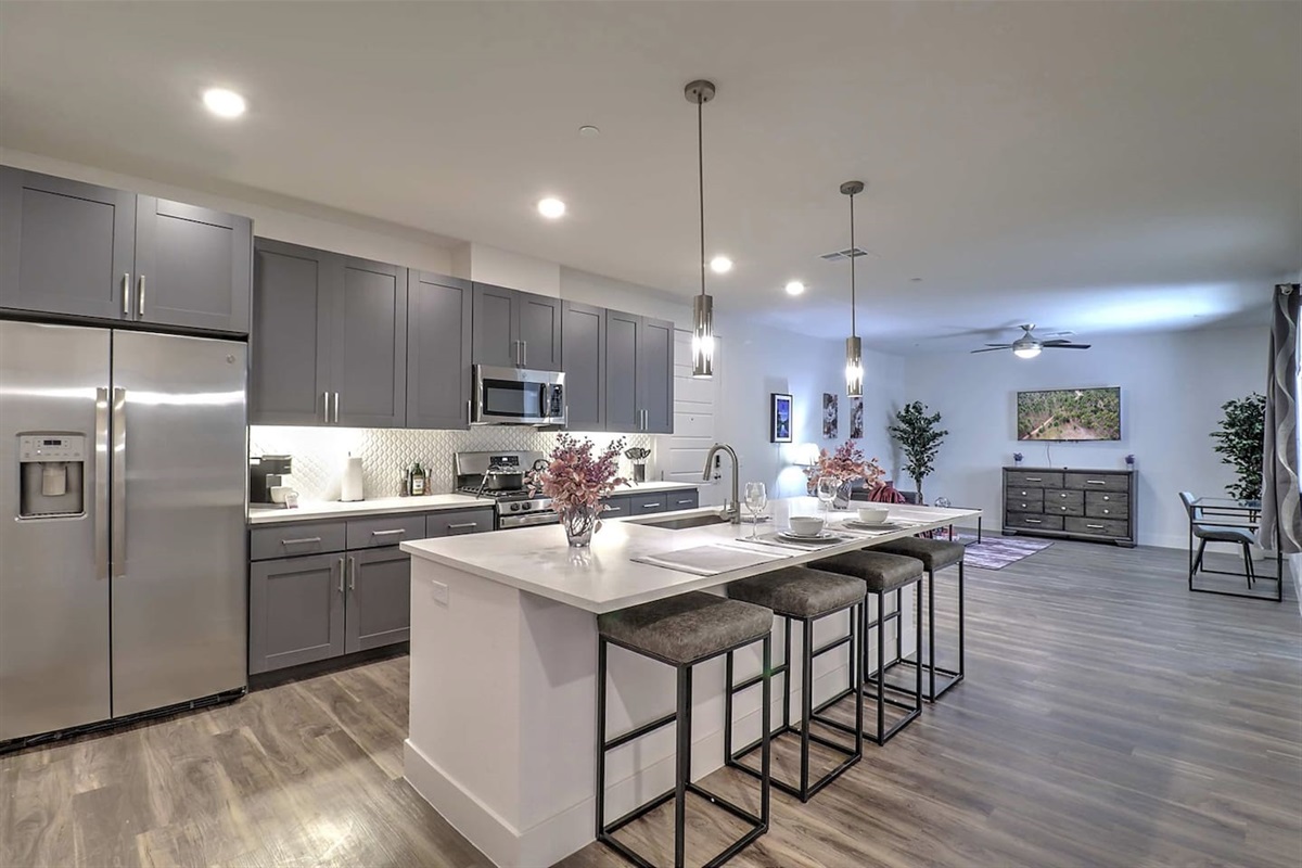 - Enjoy a spacious open-concept kitchen with sleek gray cabinets and bar   - Perfect for cooking, chatting, or enjoying meals in a cozy setting   - Modern appliances and elegant lighting enhance your home experience