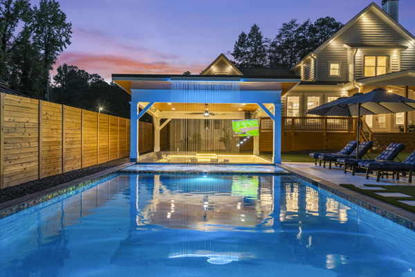 Waterfall feature into the hot tub spa with swim up bar, large pool and sun lounge chairs.