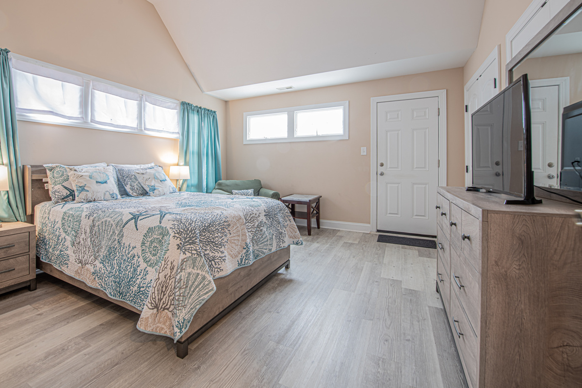 Bedroom 1 with Coastal Decor, Dresser, and Vaulted Ceilings