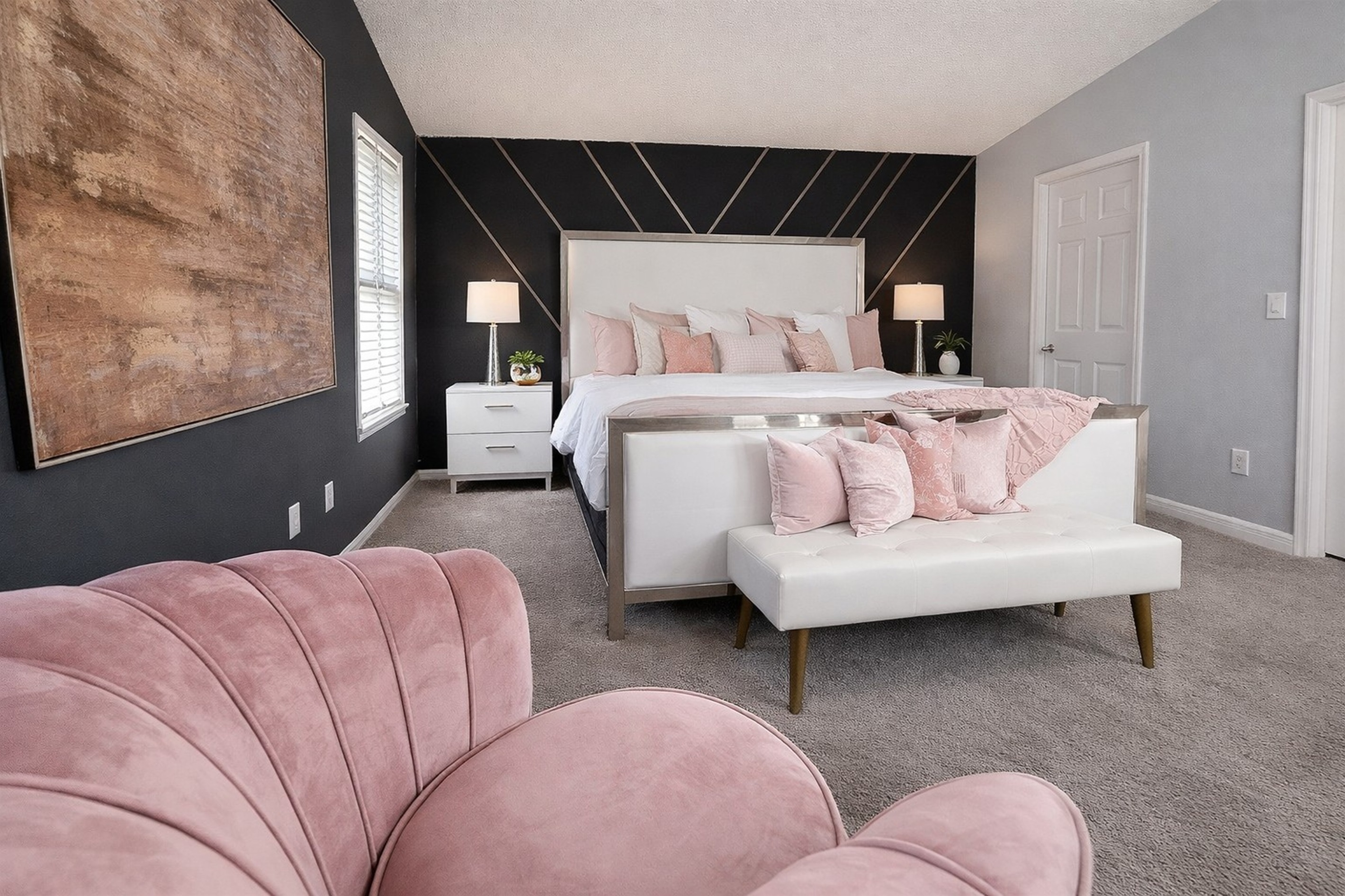Modern bedroom with a large bed, soft pink accents, and stylish wall design.