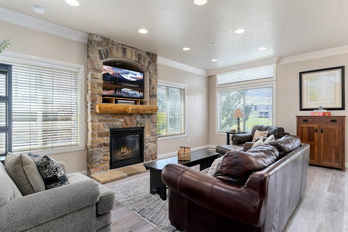 Bright and inviting living room featuring a cozy gas fireplace, abundant natural light, and comfortable seating—perfect for relaxing after a day of adventure.