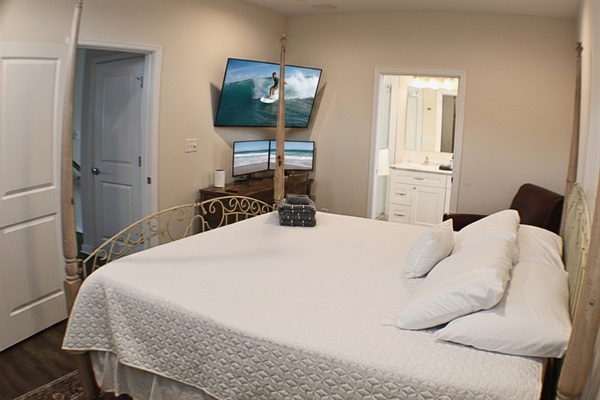 Master Bedroom: Relax in a spacious room featuring a stunning four-post bed, stylish decor and an elegant workspace with dual monitors and a large TV for ultimate relaxation.