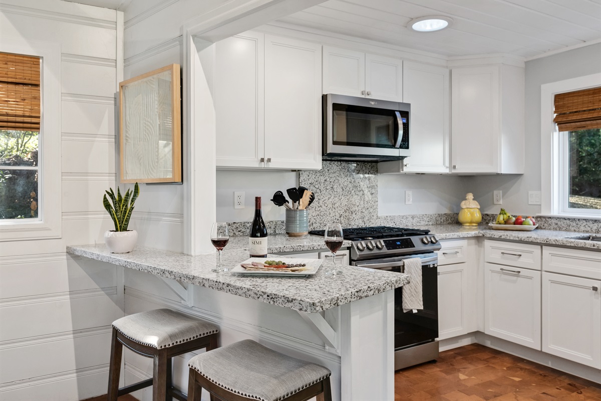 Bright chefs kitchen with granite countertops and stainless appliances.
