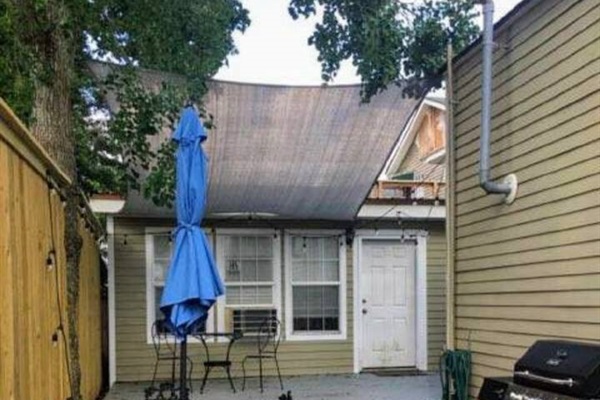 Continuation of rear patio including seating, propane grill, and privacy fence.