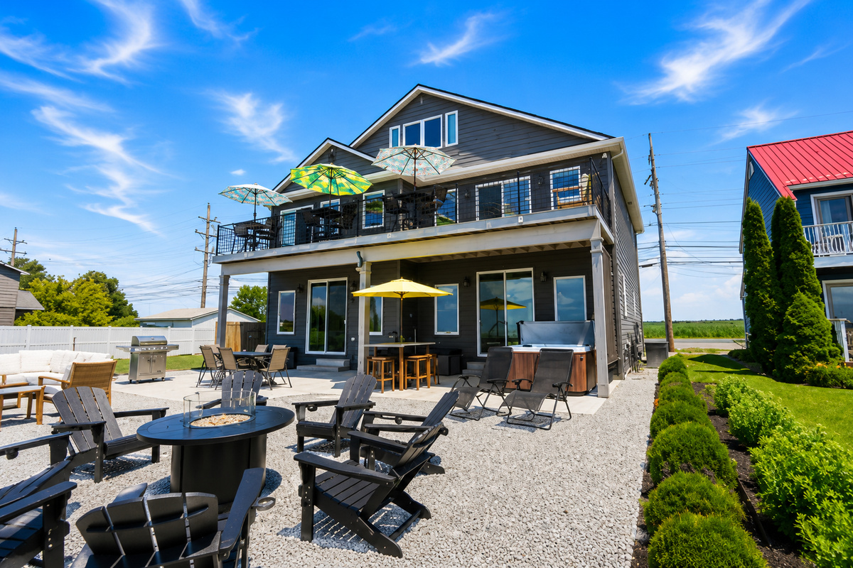 Relax in your private waterfront oasis featuring a hot tub, fire pit, outdoor bar, BBQ grill, and multiple seating areas—perfect for entertaining and enjoying the views.