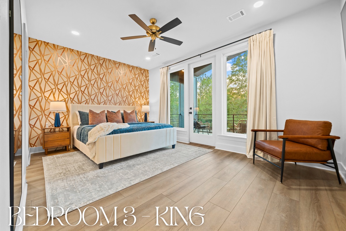 A sunlit king bedroom with large windows that bring in the beauty of nature &ndash; a peaceful place to relax and recharge.