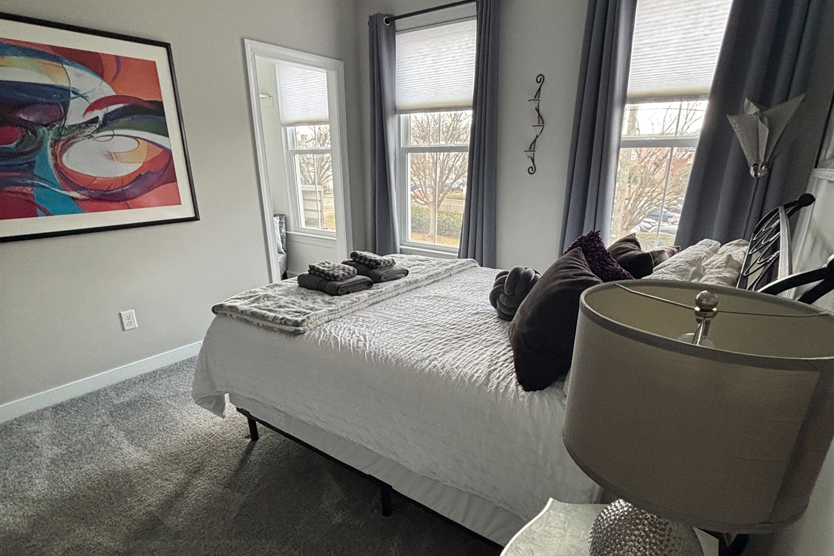 Queen Bedroom 3: Relax on a plush bed adorned with vibrant pillows and gentle natural light. Added Room Darkening Shades