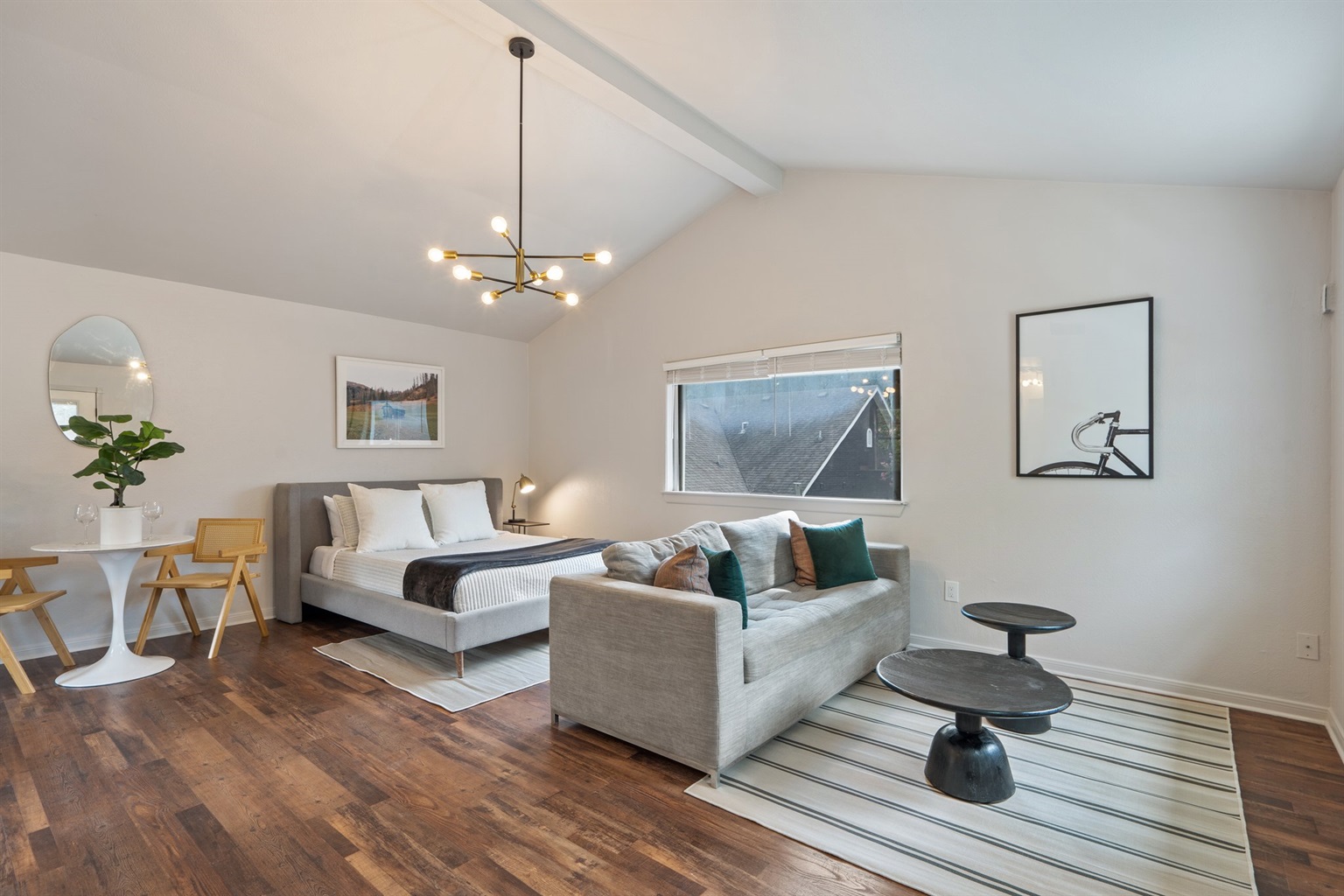 Detached Studio open-plan living area with Queen Bed, sofa seating, pendant lighting, and hardwood floors. Private self-contained unit with ensuite bathroom, fully equipped kitchen, and sleeping for up to 4 guests.
