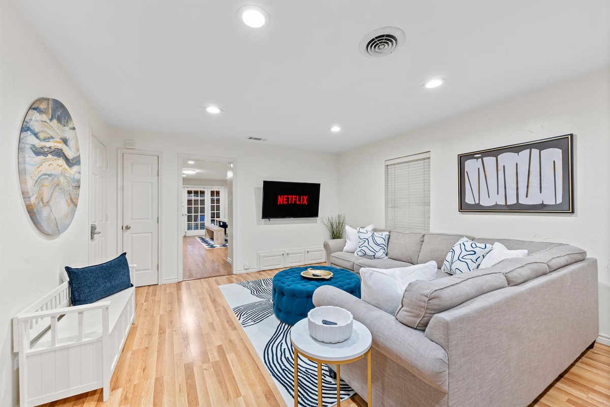 Unwind on a plush sectional with ambient lighting and a mounted smart TV for streaming your favorite shows.