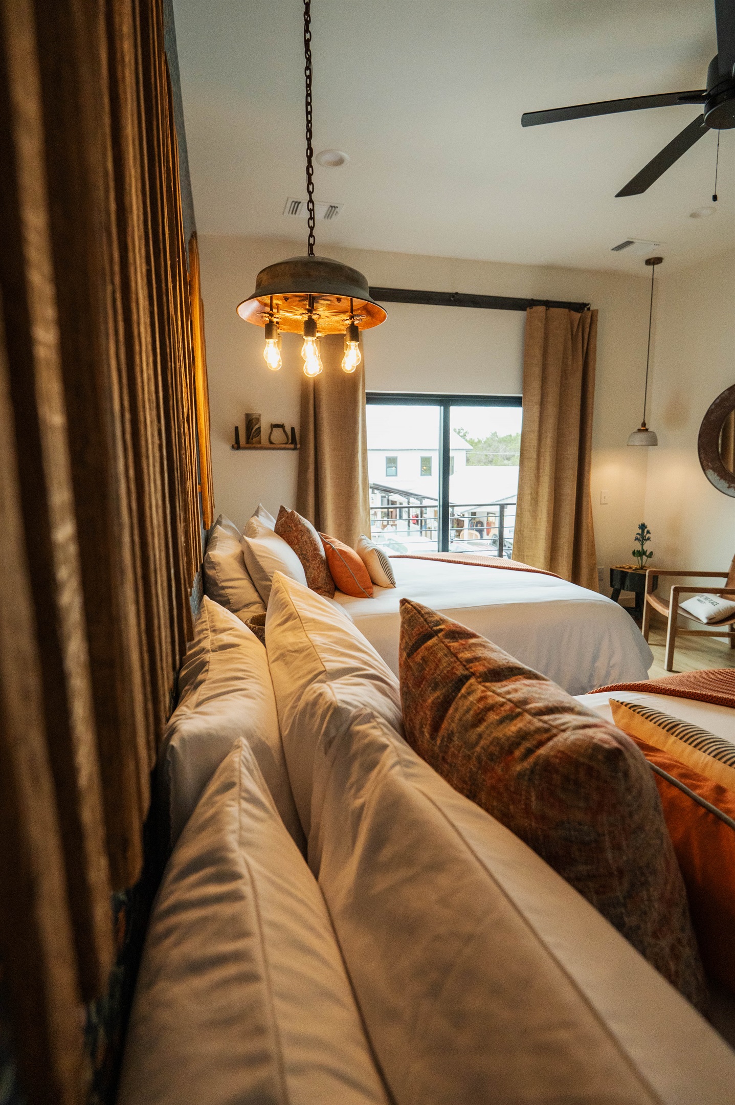 The Corral Suite bedroom — two queen beds, a bright window, and premium Comphy linens in a modern Western setting.