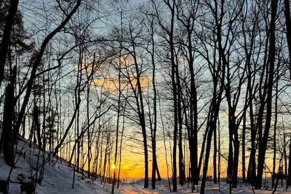 Stroll down this magical snow-dusted trail lined with towering trees as the sun sets over Lake Michigan. A perfect moment of winter calm and natural beauty