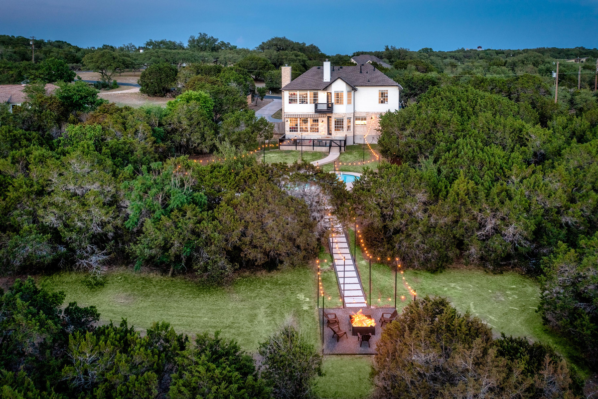 A scenic pathway winds through mature oaks toward this Hill Country estate.