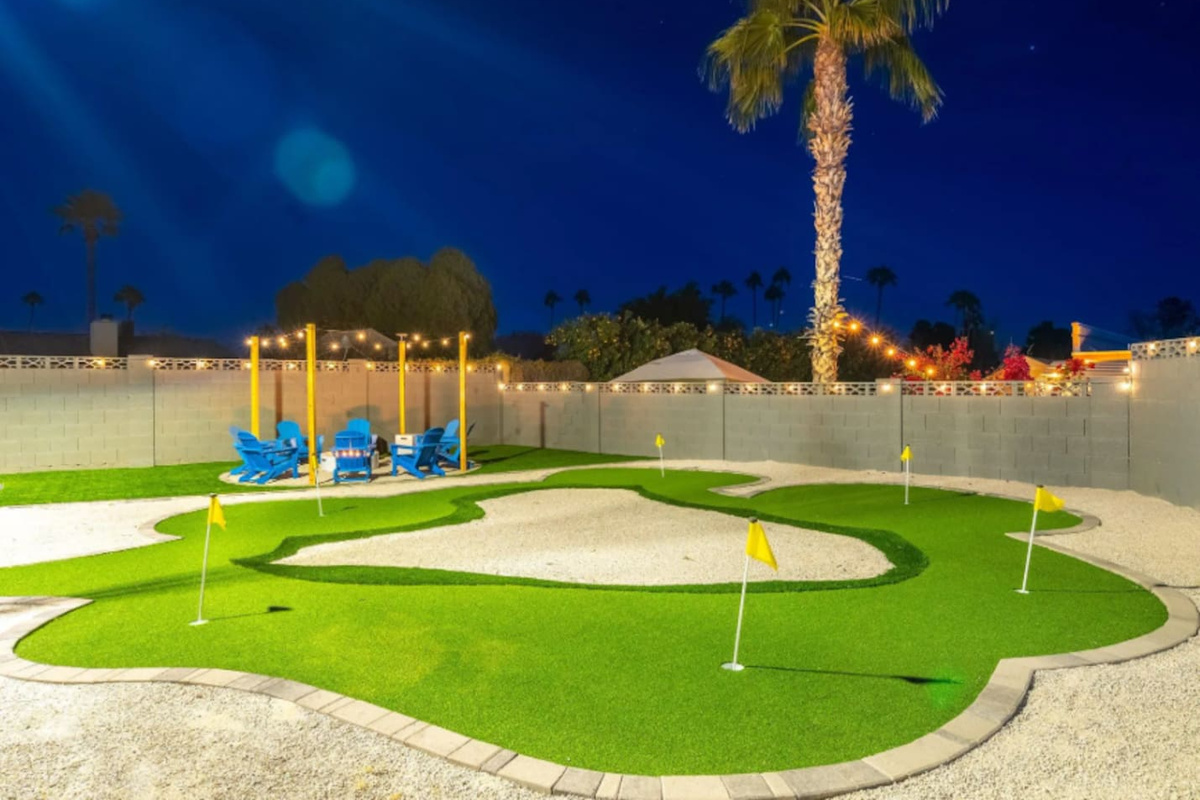 A backyard putting green under string lights and palm trees, because vacation should include a few rounds of mini golf before bed. Multiple holes mean the whole group can play at once.
