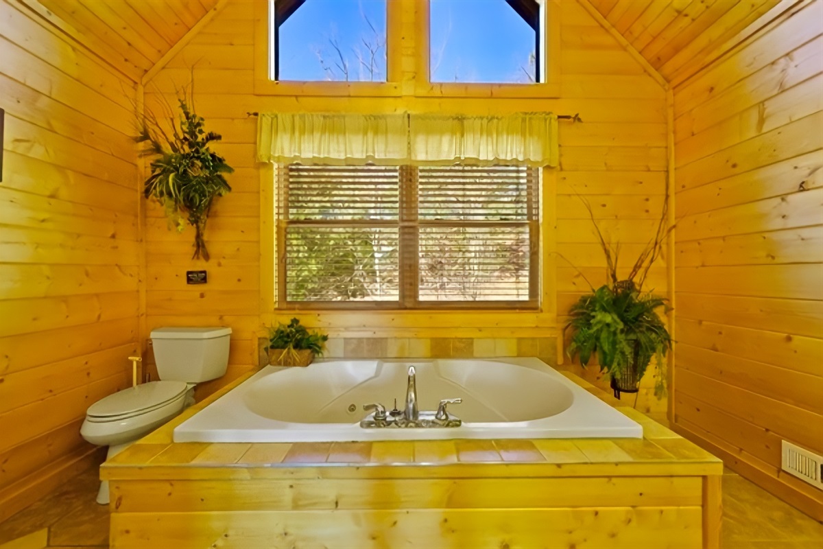 Bathroom #2 – Soak in a large jetted tub framed by warm wood paneling beneath the golden glow pouring through tall windows a quiet retreat where nature’s light and warmth meet pure relaxation.