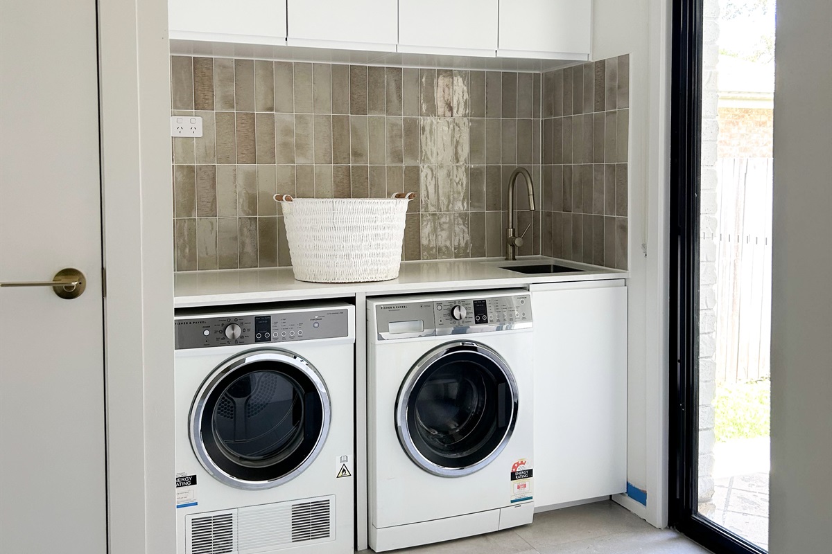 The laundry has a front-load washer, separate dryer and bench space, making everyday washing simple during the stay.