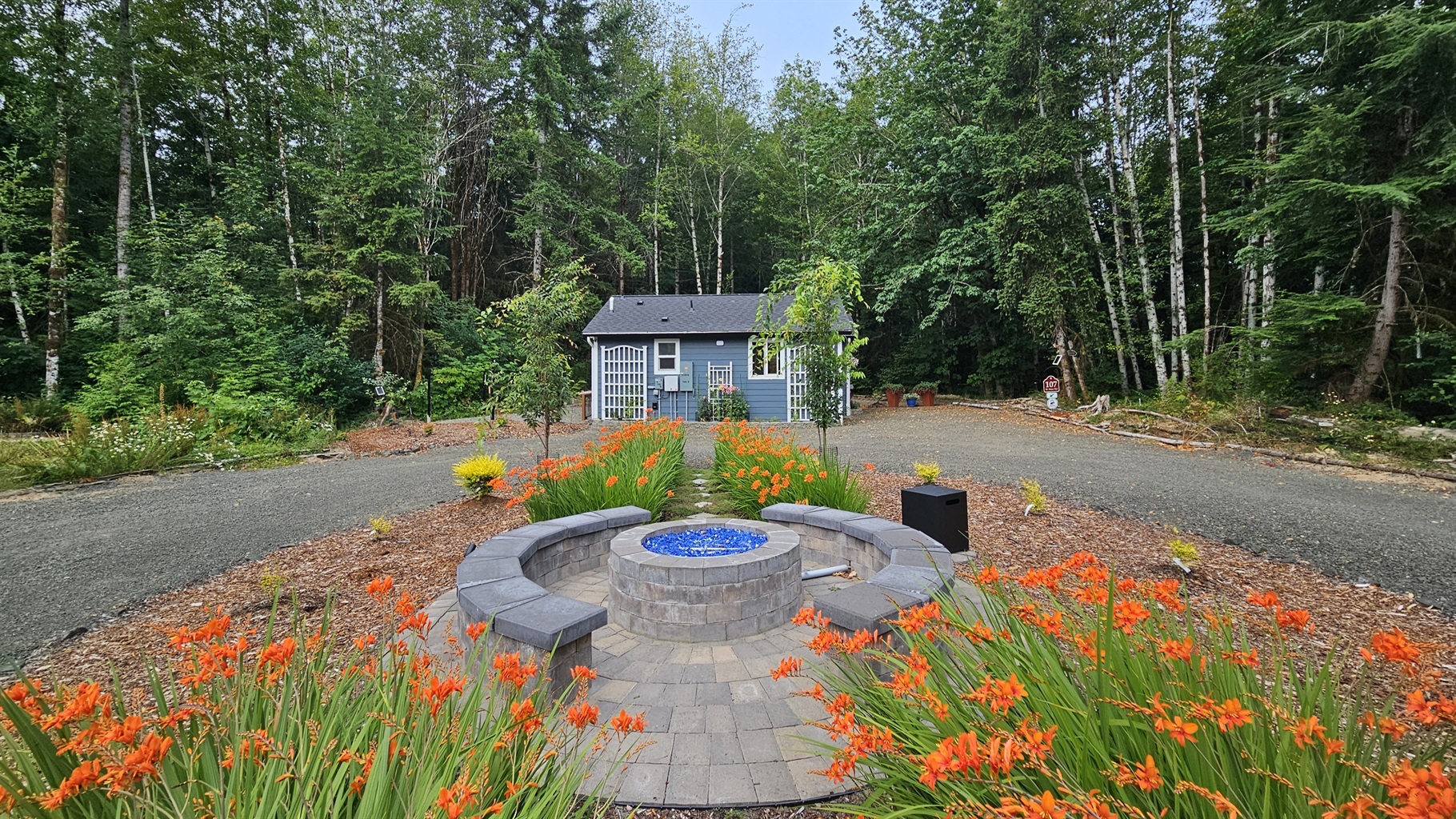 Propane fire pit and seating area between the 105-RV Site and 107-Cottage