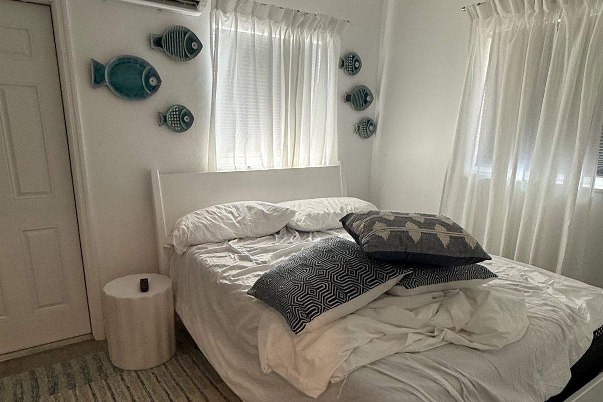 Drift into comfort in this bright and airy bedroom, featuring plush bedding and a calming coastal feel.