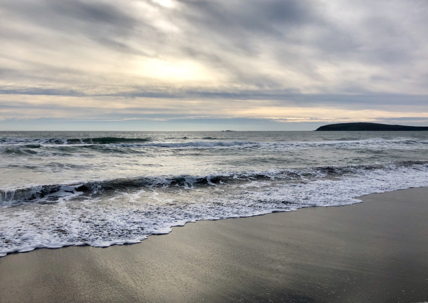 Foamy waves beneath a softly lit cloudy sky