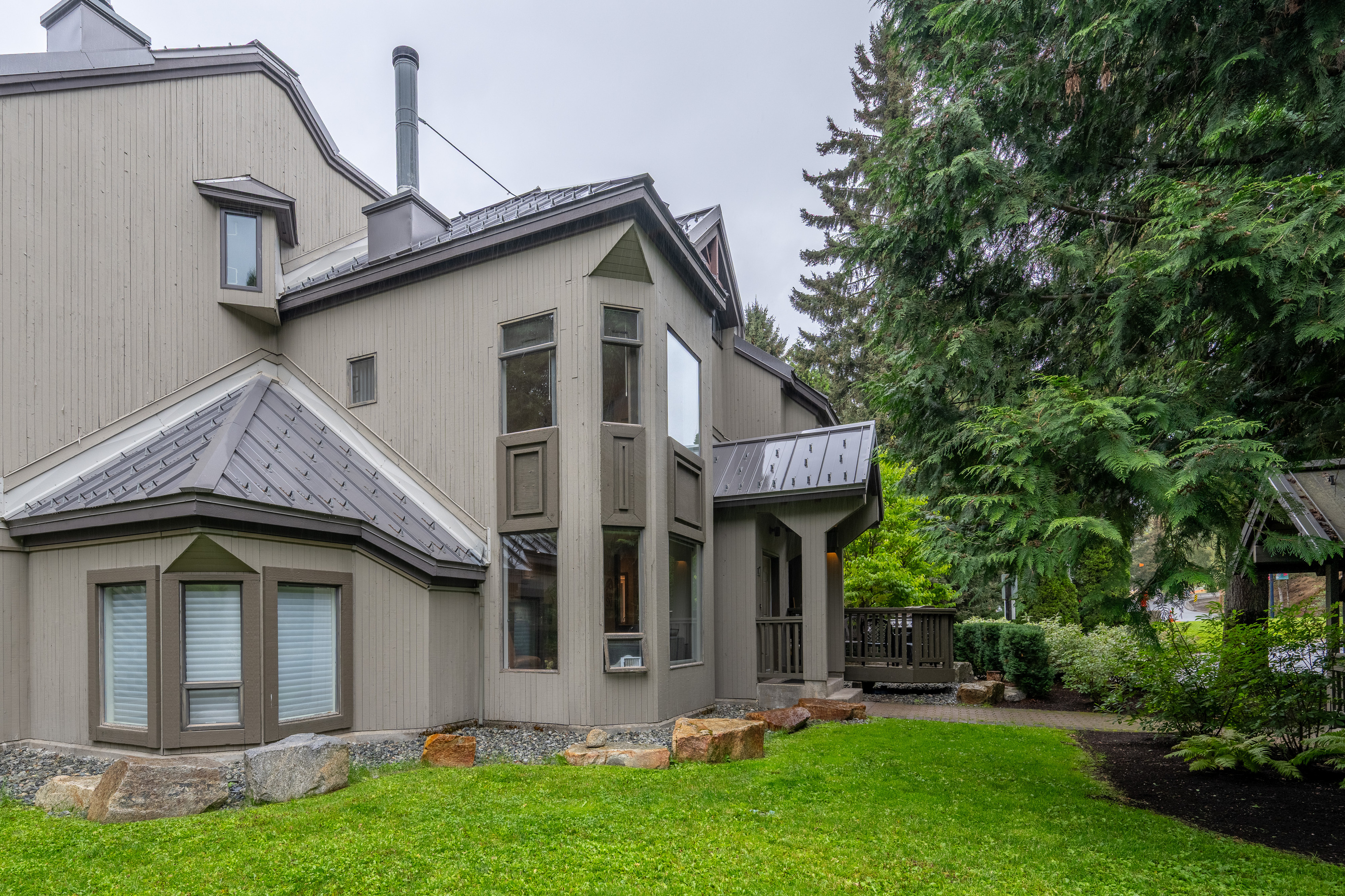 The rear and side of Gables #17, a lawn and mature trees, giving this end unit no neighbours above, below or beside.
