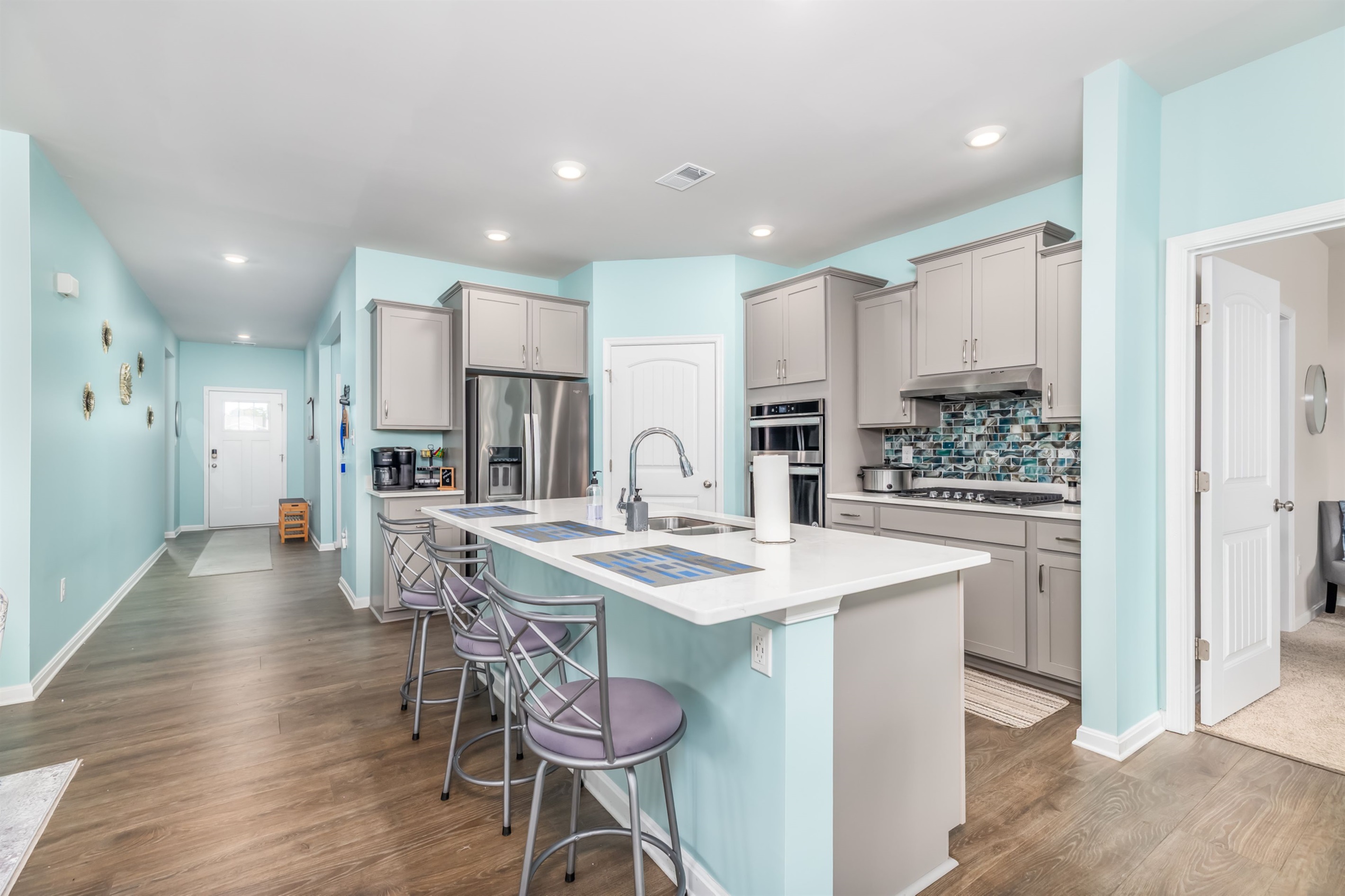Step into a sunlit foyer painted in coastal hues, with a durable runner rug and convenient bench—perfect for shedding sandy shoes and greeting guests.