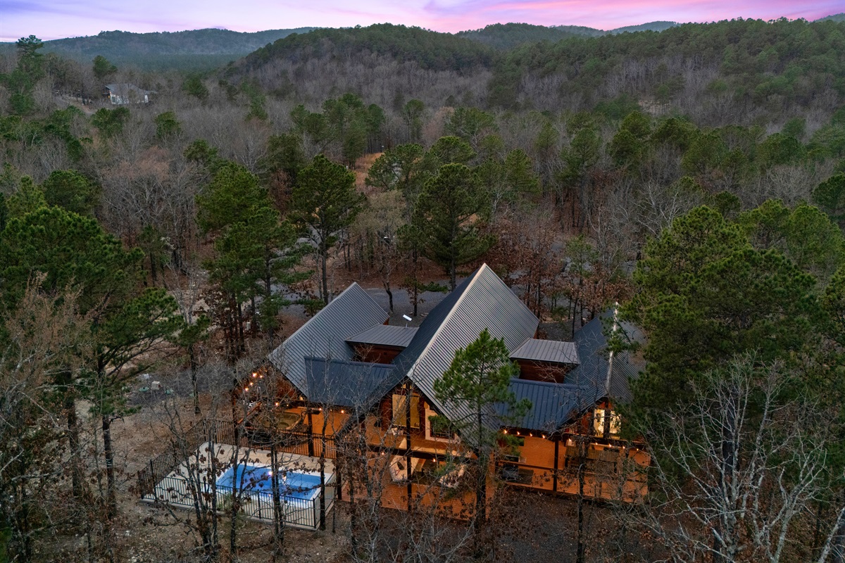 This aerial view highlights the peaceful setting, where the cabin sits privately among the trees with the pool adding a fun and relaxing touch to the outdoor space.