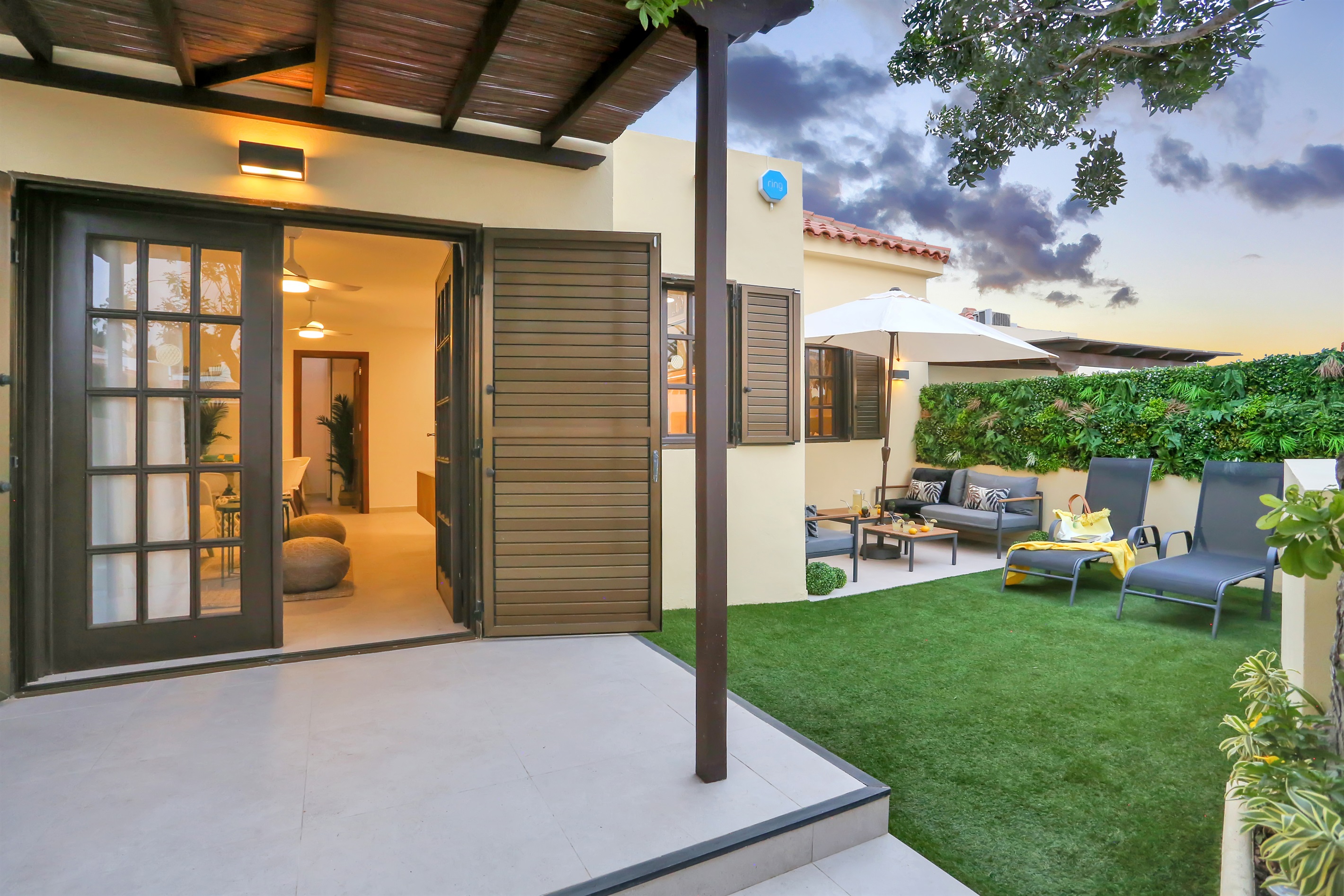 Charming private garden at sunset with a covered terrace and direct access to the interior, creating a warm and inviting atmosphere.