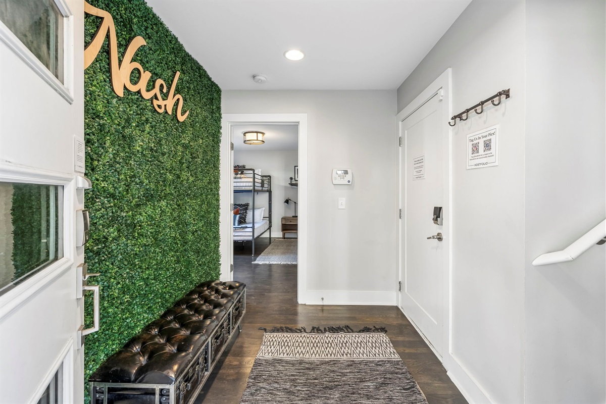 Eye catching artificial green wall brings a vibrant pop of nature inspired style indoors - Paired with a tufted leather bench for a cozy spot to sit, drop bags, or snap a photo - Perfect Instagram worthy moment that adds flair to the hallway or entryway