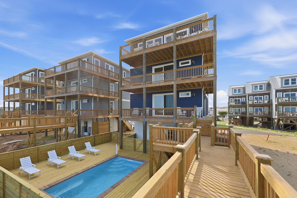 Aerial overview of the shared pool area and surrounding multi-level beach homes, highlighting the central pool deck, private walkways, and close ocean access within the community
