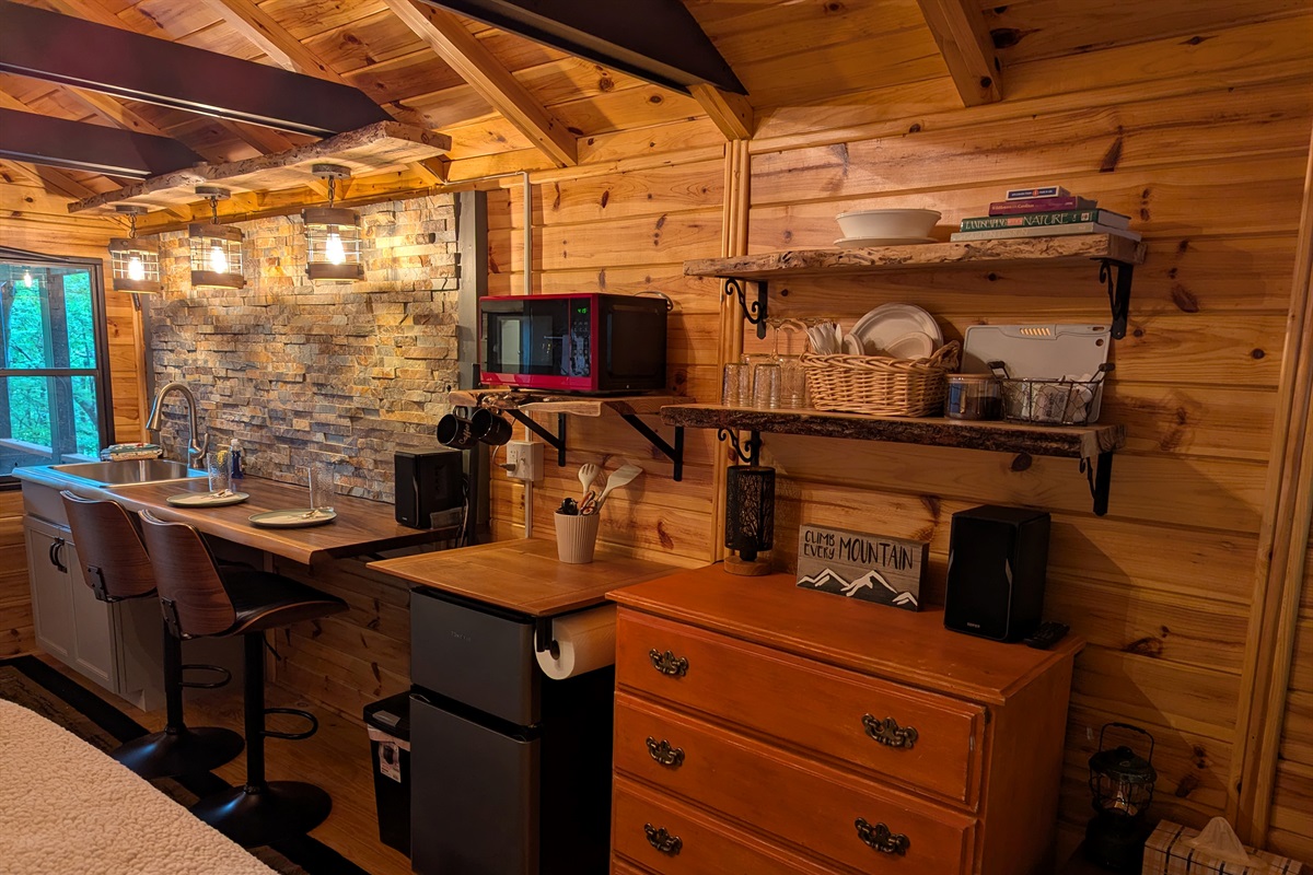 Microwave, Mini Fridge, Coffee Maker, Electric Kettle, and Hot Plate with some pots and skillet provided. 