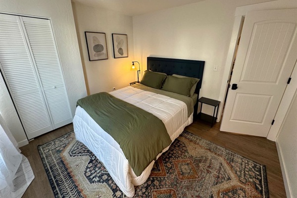 This bedroom features a queen bed, black out curtains, and generous closet space. 