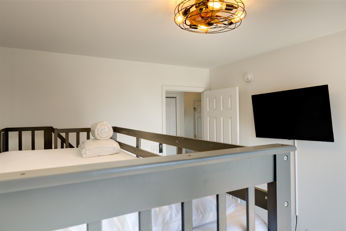 A fun and cozy space designed for kids, featuring sturdy bunk beds, a wall-mounted TV, and warm lighting