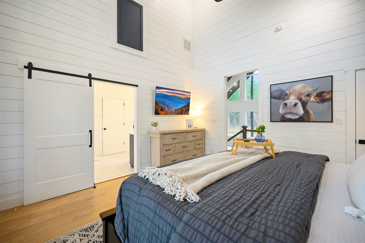 2nd King bedroom featuring barn doors, custom finishes, and serene woodland views.